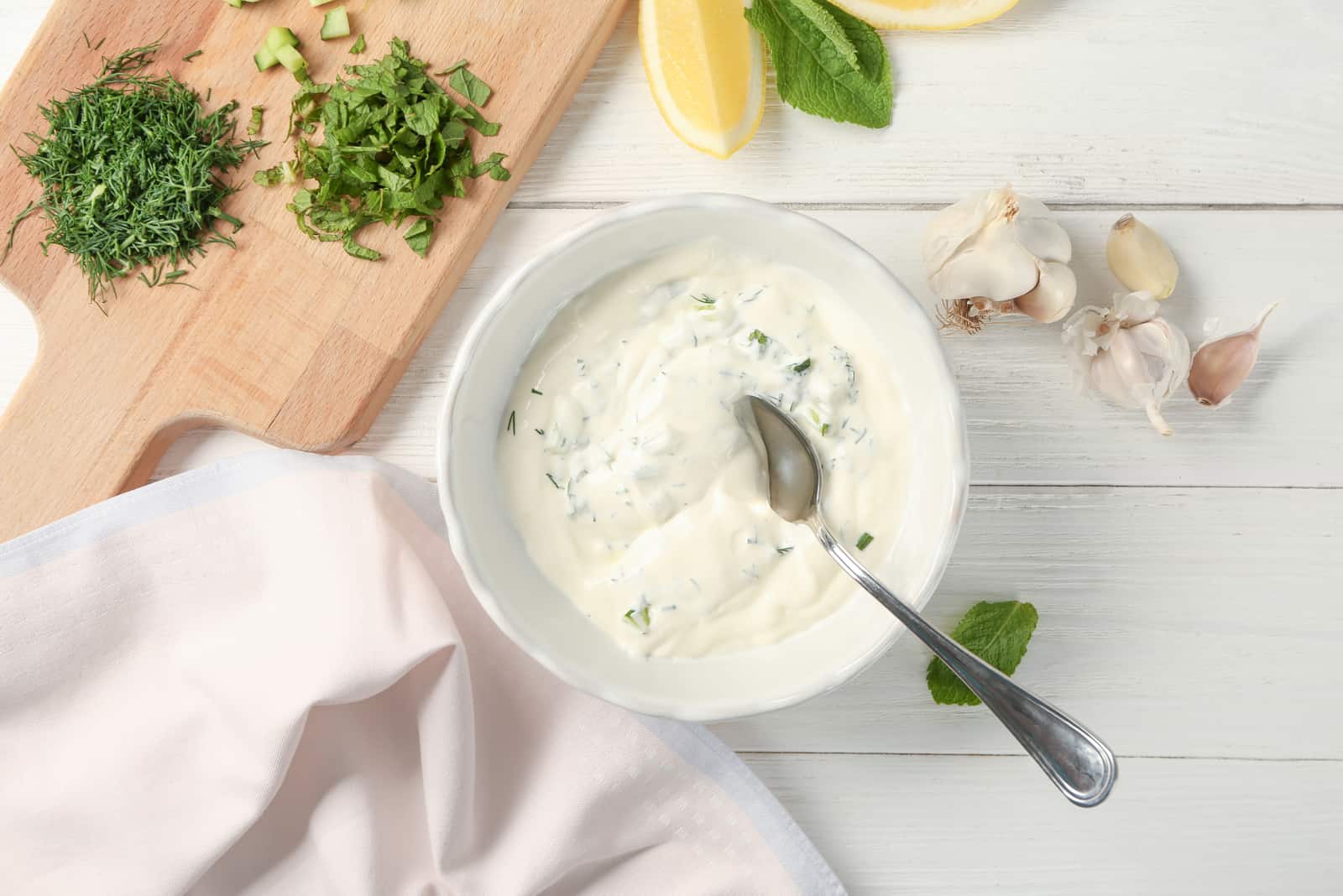 Deliciosa salsa de yogur en un cuenco con ingredientes sobre fondo de madera
