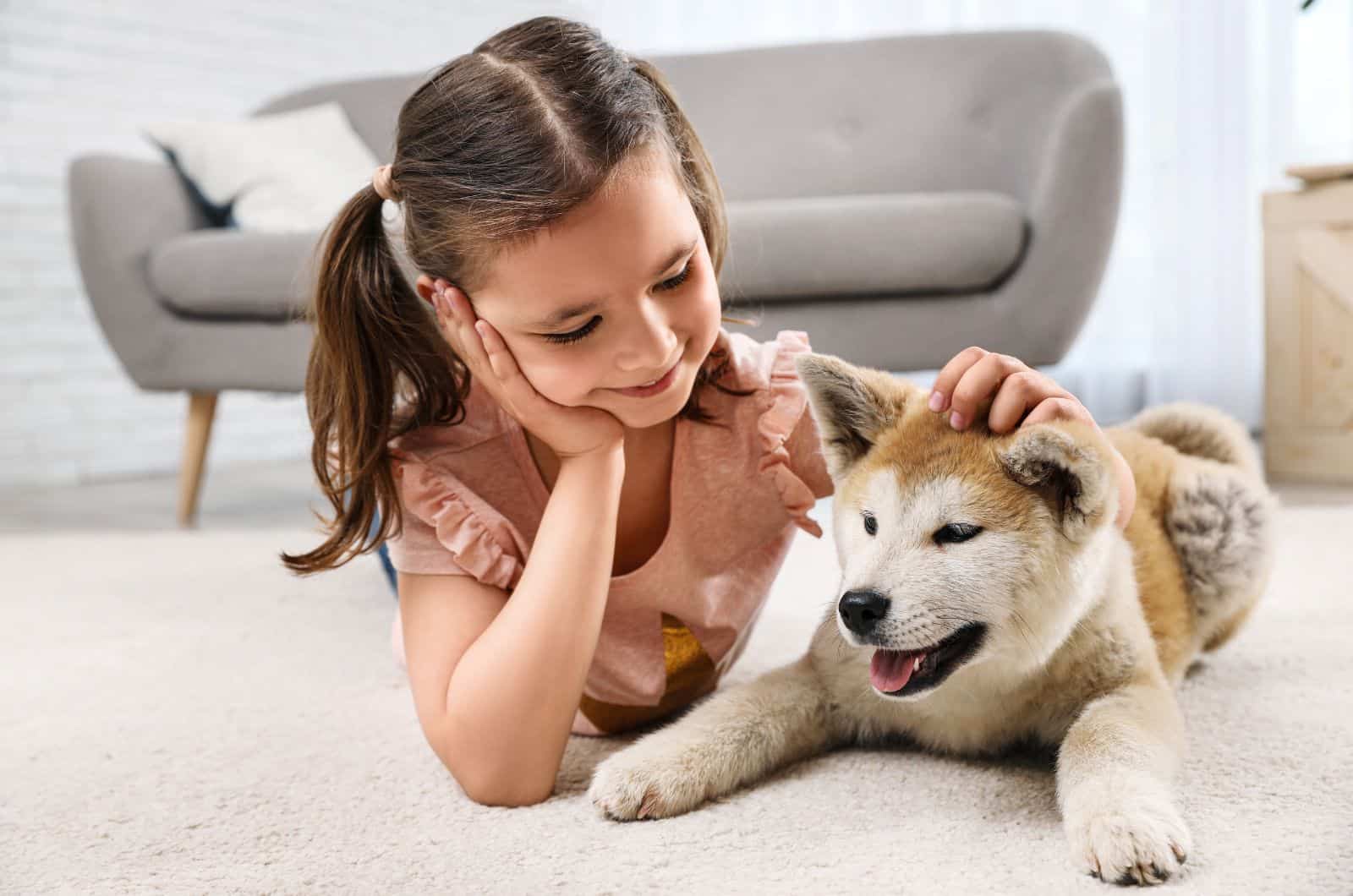Chica feliz con perro Akita Inu en el piso