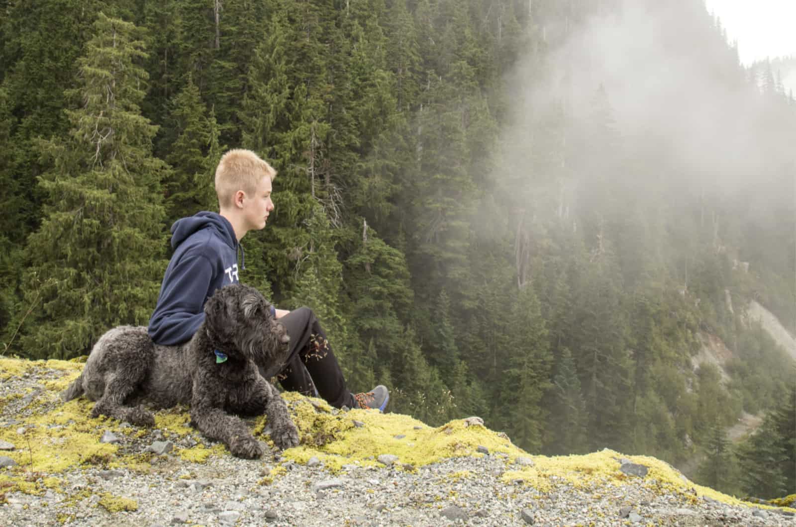 Mezcla de Irish Wolfhound y Poodle sentado con un niño en un acantilado