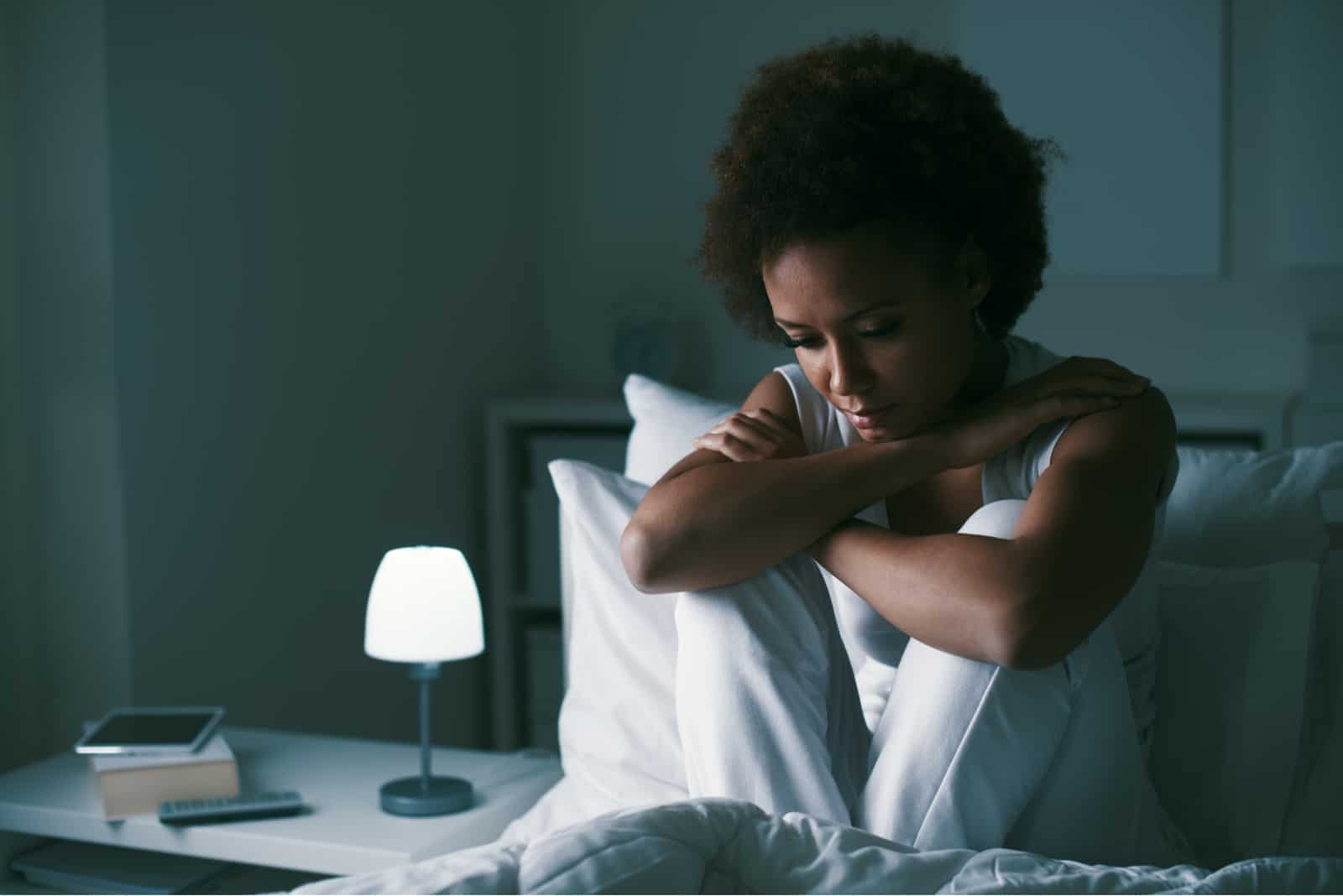 Mujer triste y deprimida sentada en su cama tarde en la noche