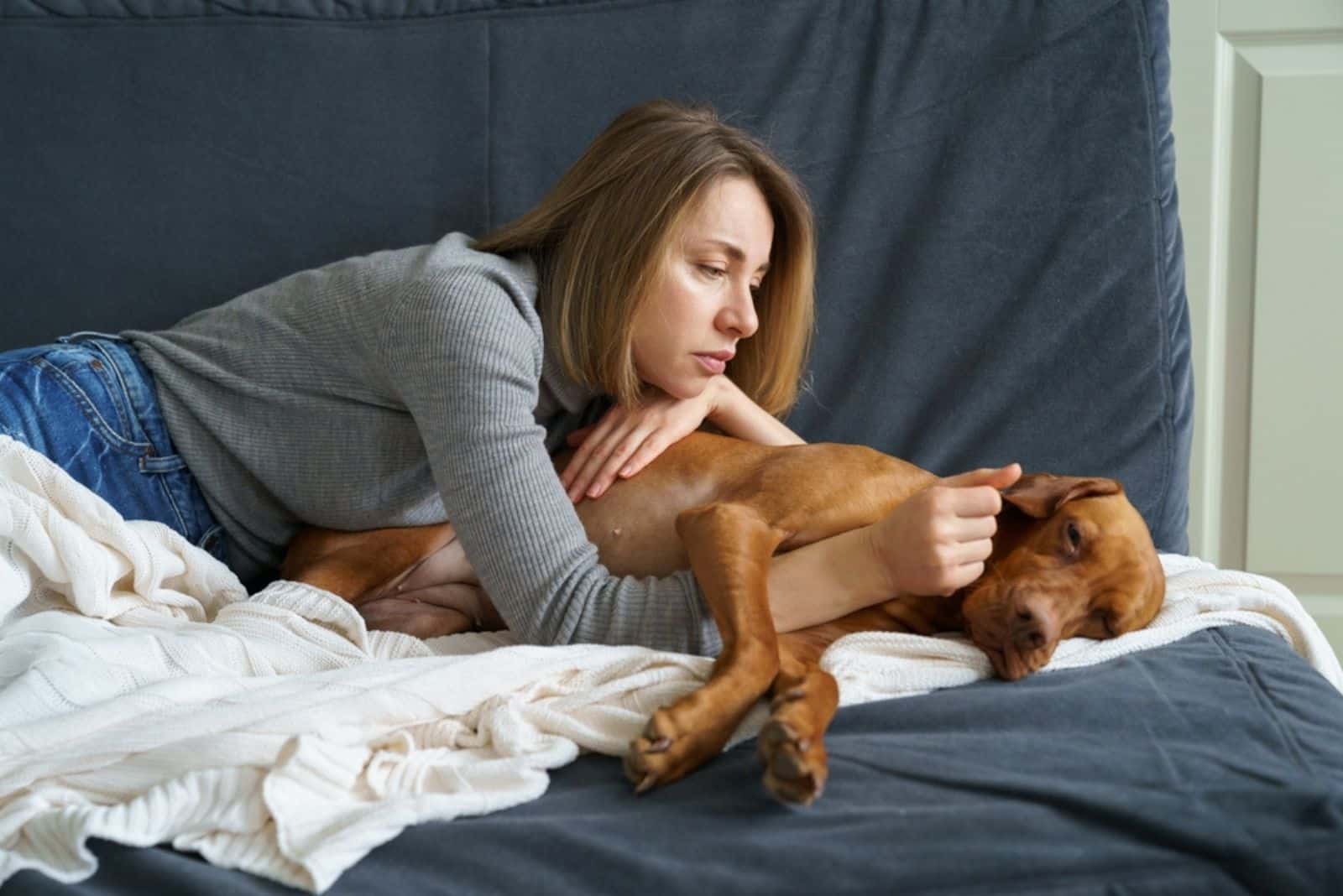 Mujer preocupada cuidando a un perro viejo debilitado