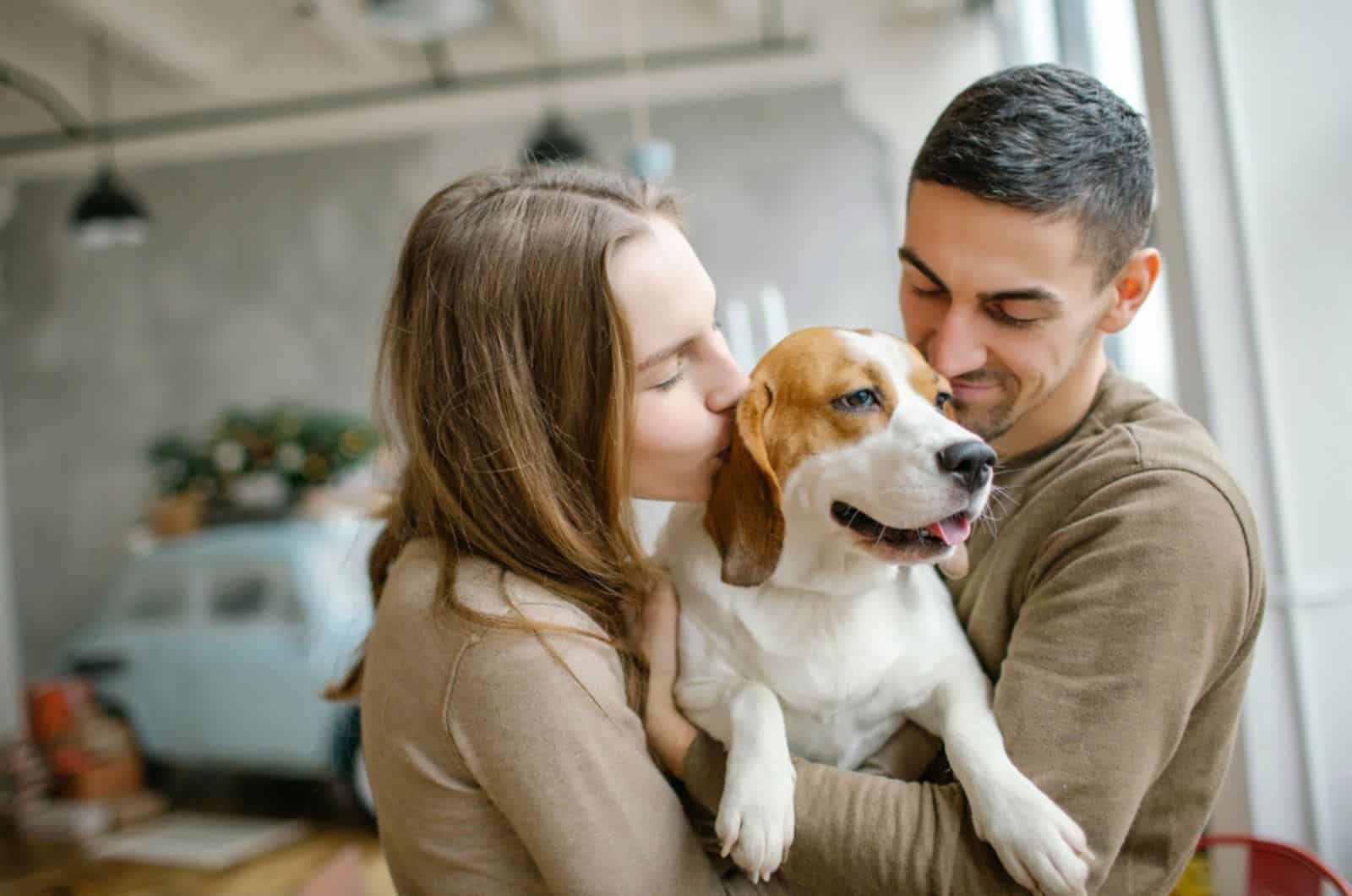 una pareja abrazando a su perro en el comedor