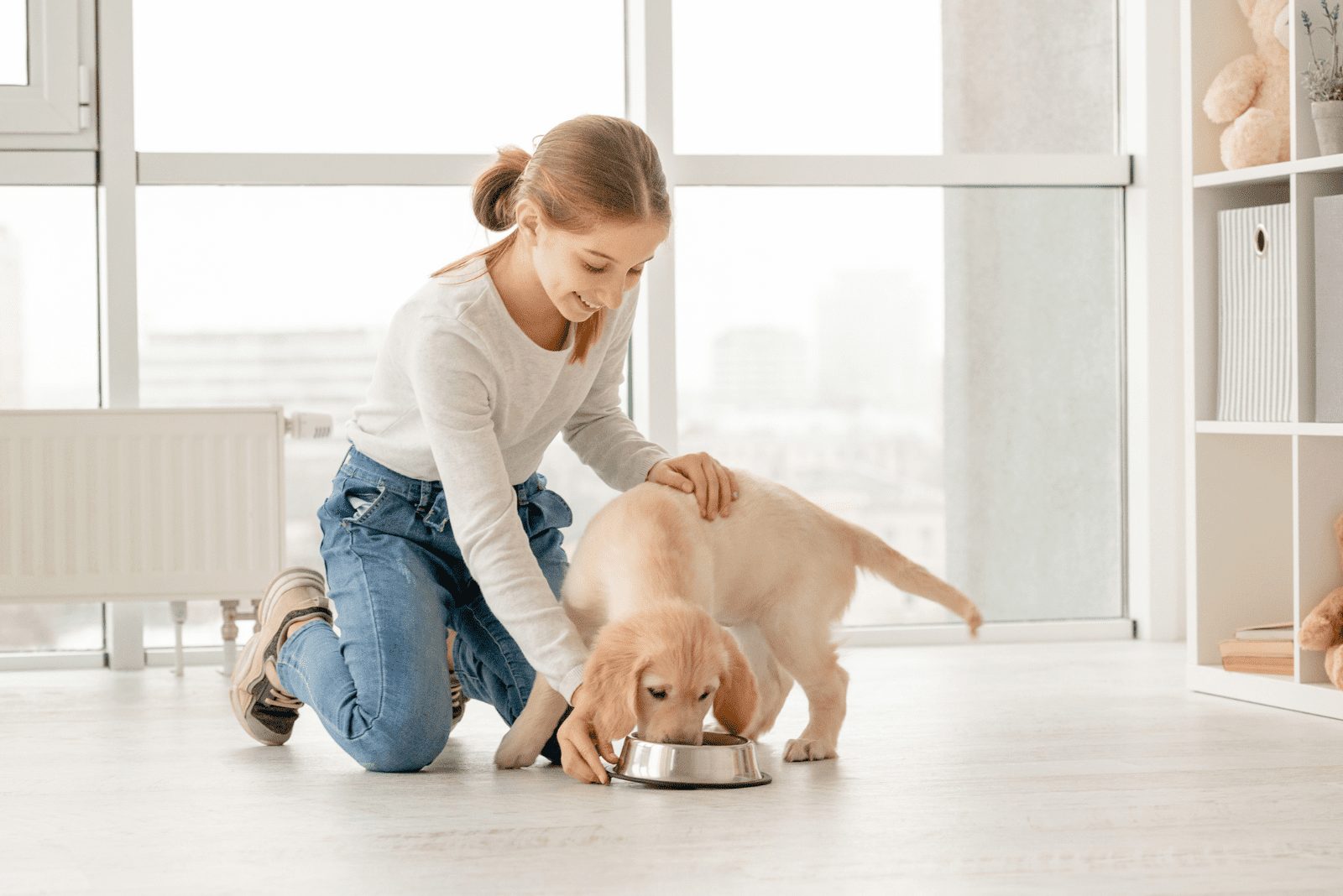 una mujer sonriente alimenta a un golden retriever