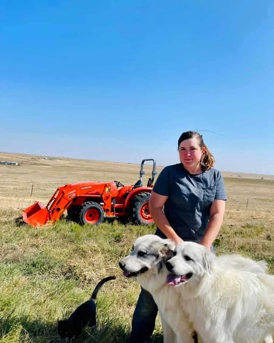 una mujer de pie con un Colorado Mountain Dog