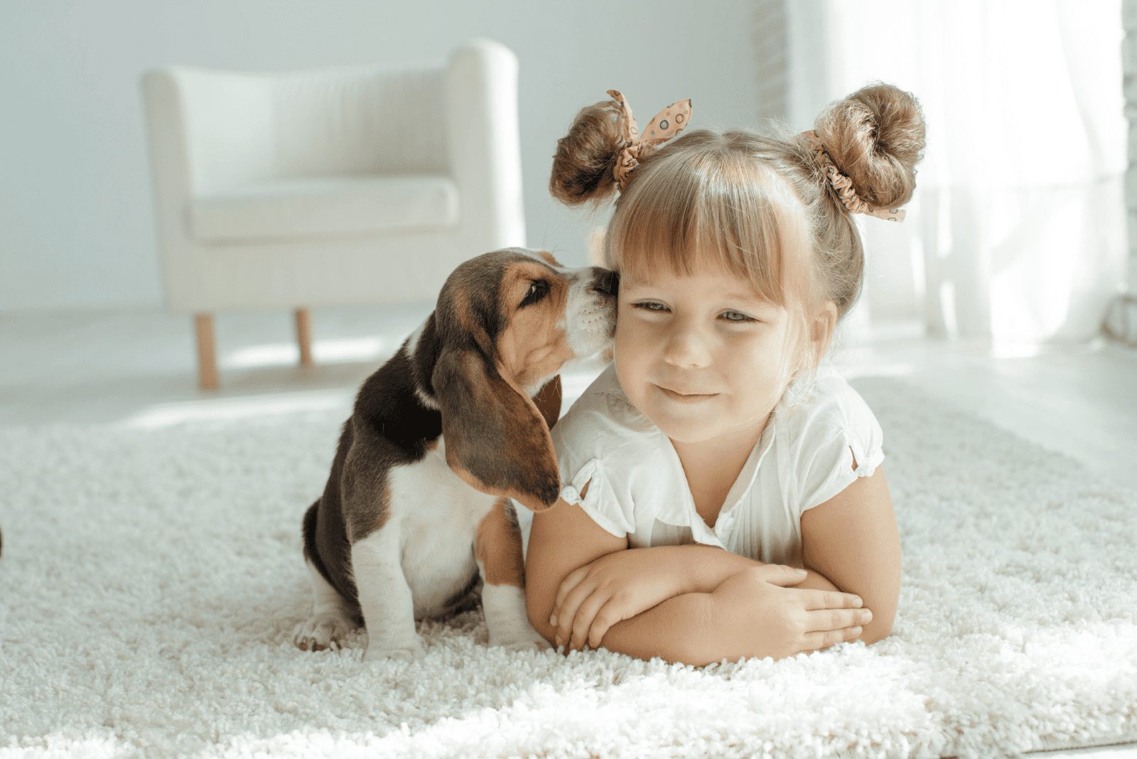 un perro adorable besa a una niña pequeña acostada en el suelo