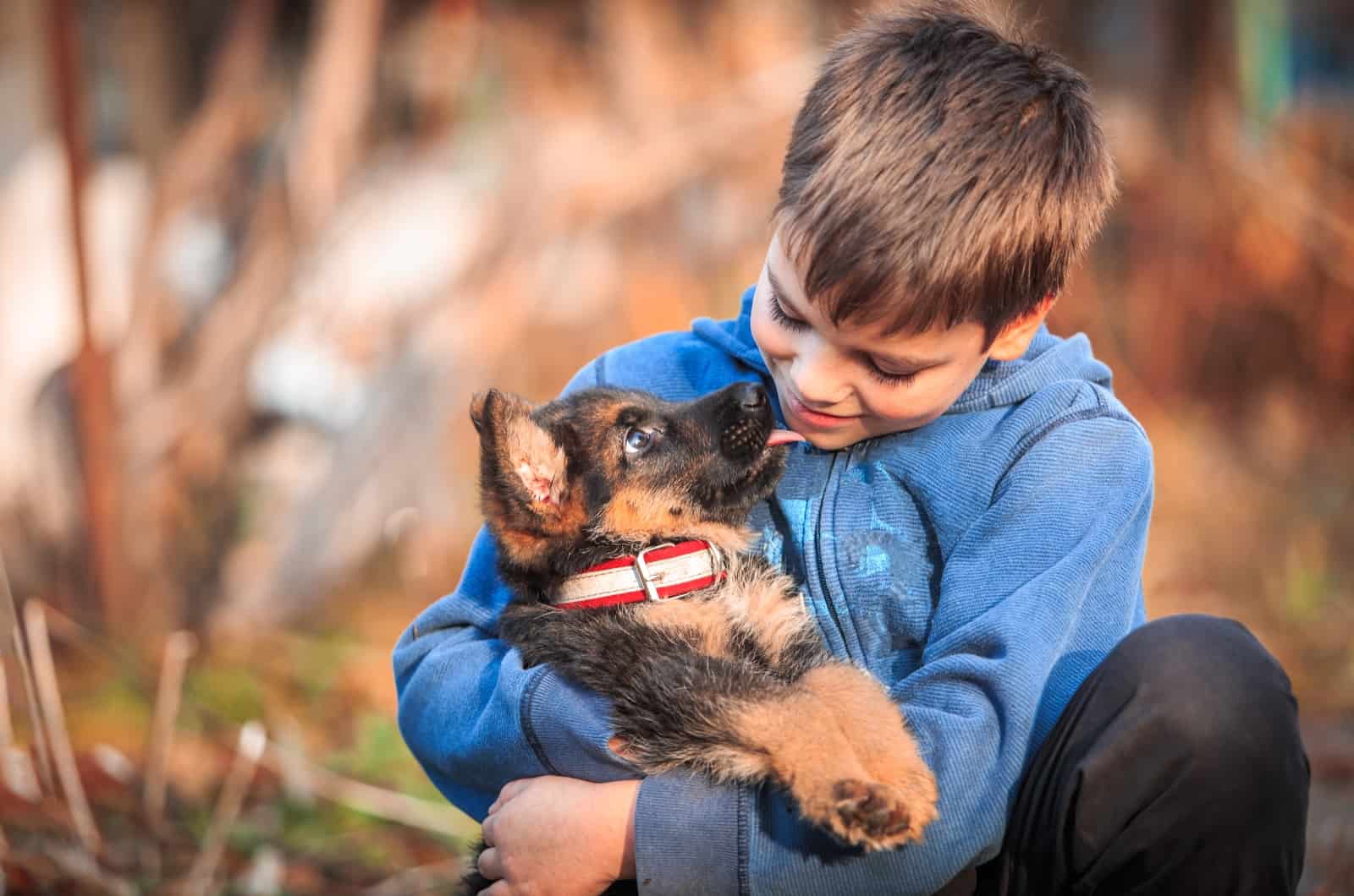 niño sosteniendo un cachorro de pastor alemán