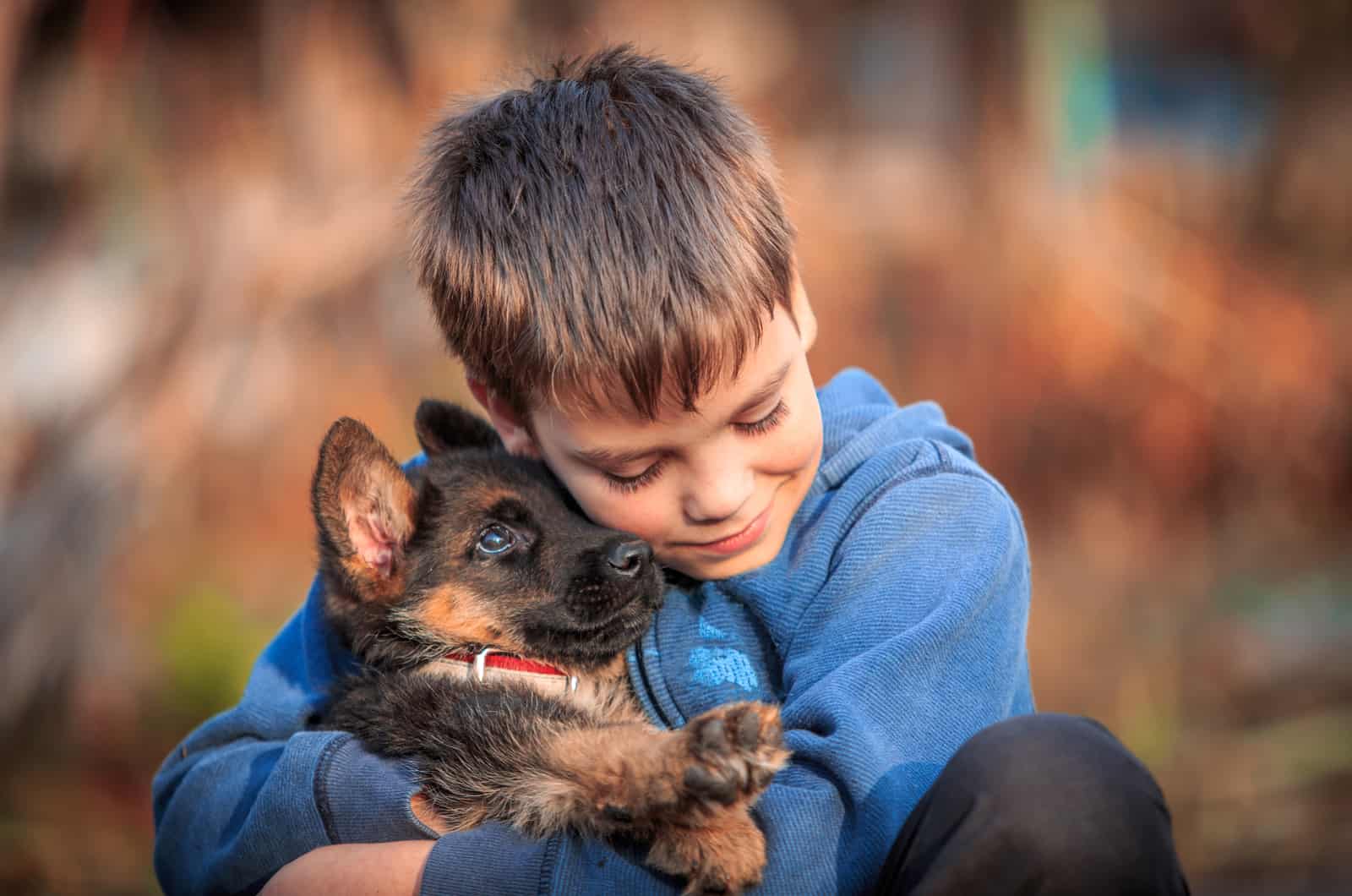 niño sosteniendo su cachorro de pastor alemán