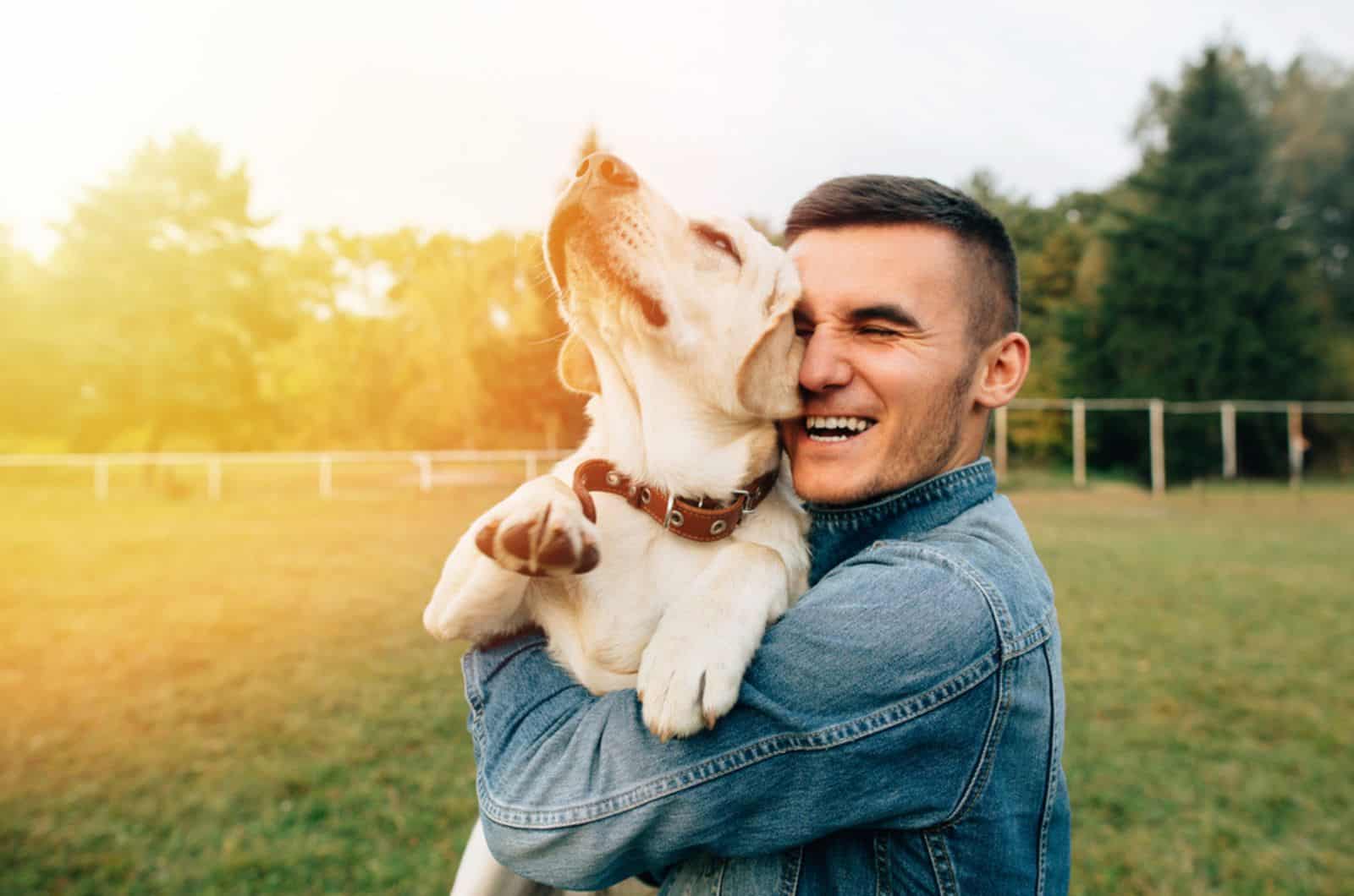 hombre feliz abrazando a su perro en el parque