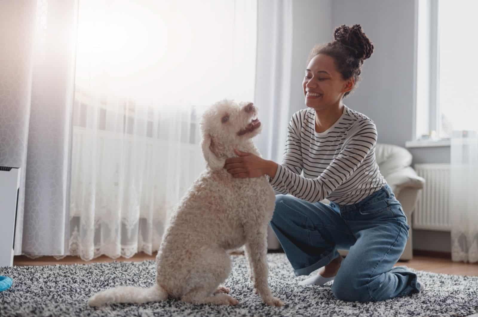 mujer feliz jugando con un perro feliz en la alfombra