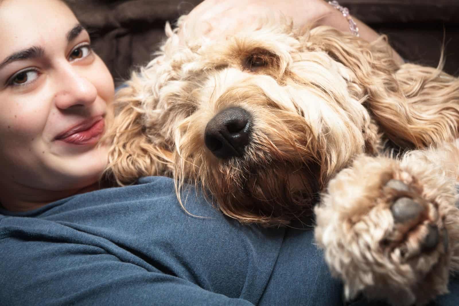 joven feliz abrazando a un goldendoodle estándar