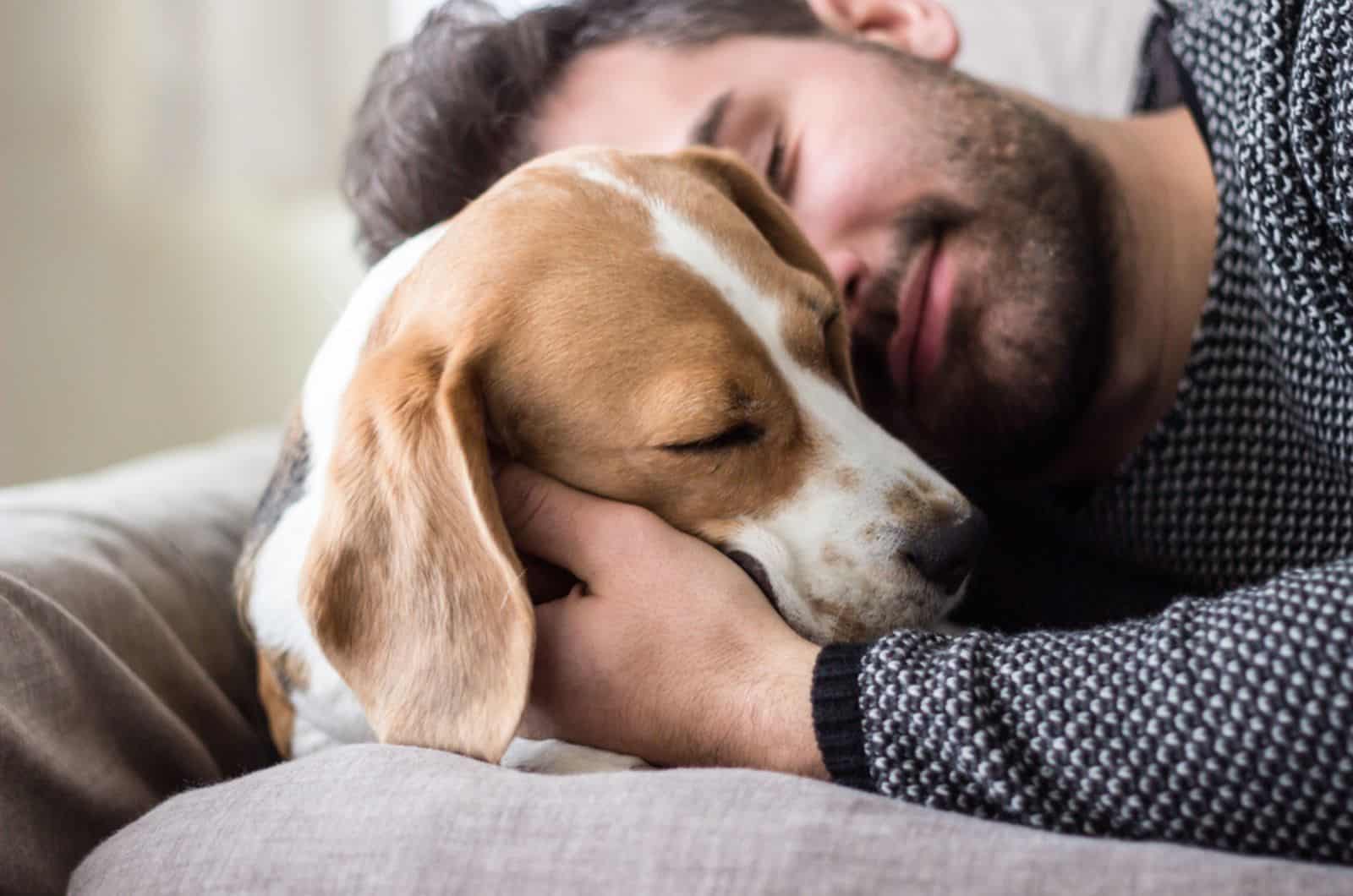 hombre abrazando a su perro en el sofá