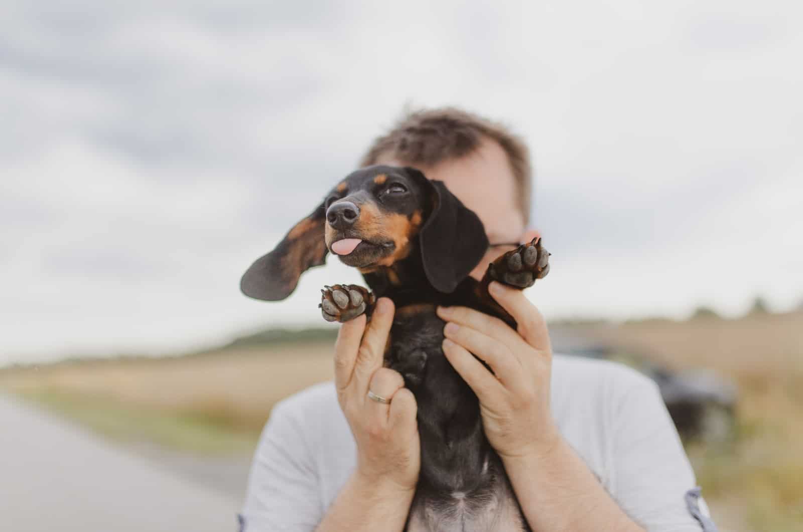 hombre sosteniendo a su cachorro dachshund