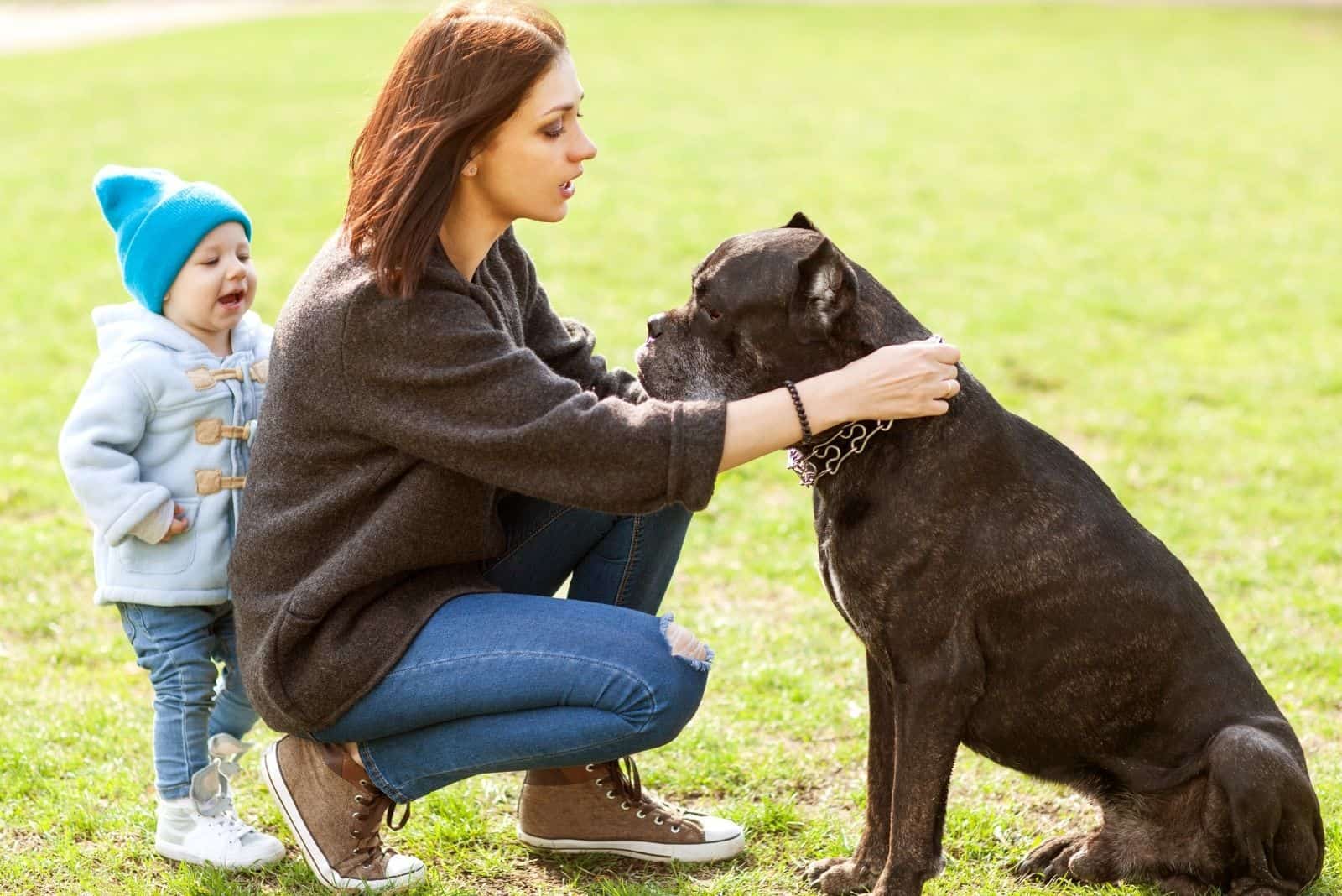 madre e hija acariciando un cane corso en el parque