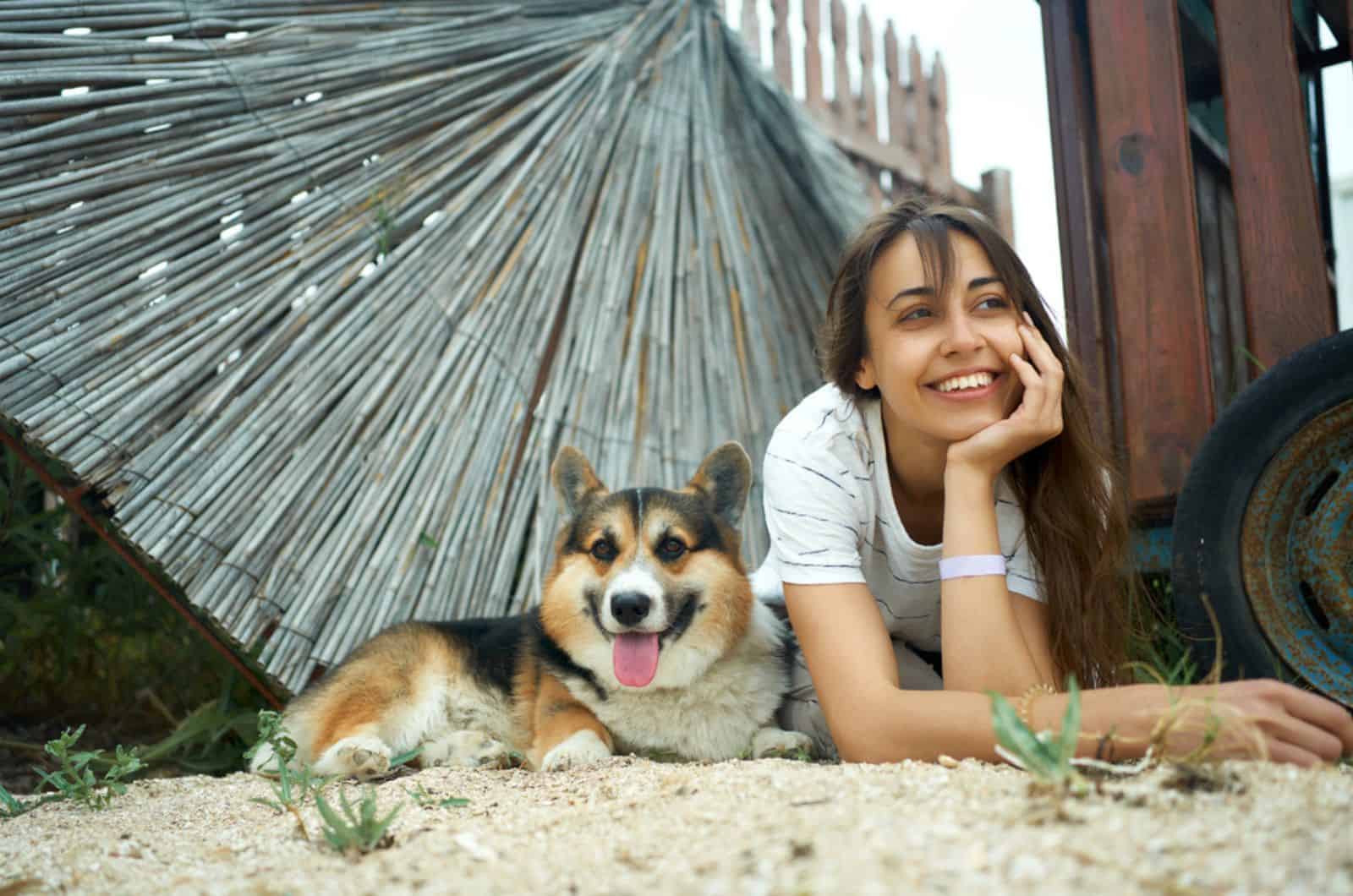mujer positiva con su perro corgi galés en el suelo