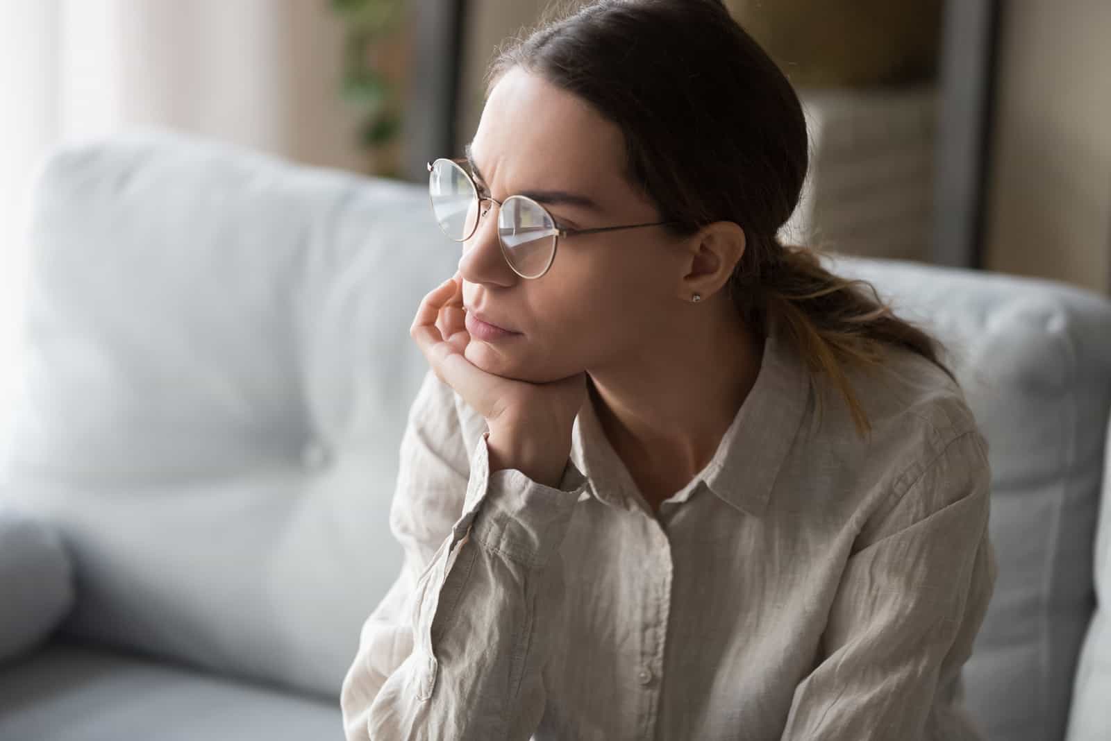 mujer seria con gafas sentada en pensamientos profundos