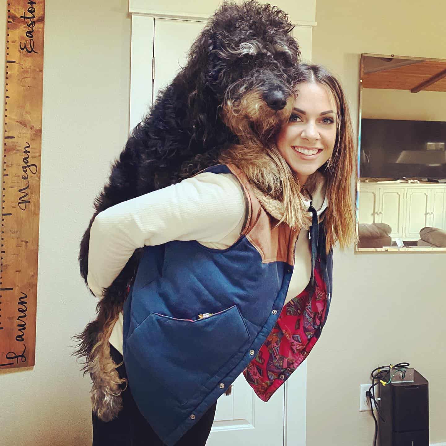 mujer cargando un gran perro rottie doodle en su espalda