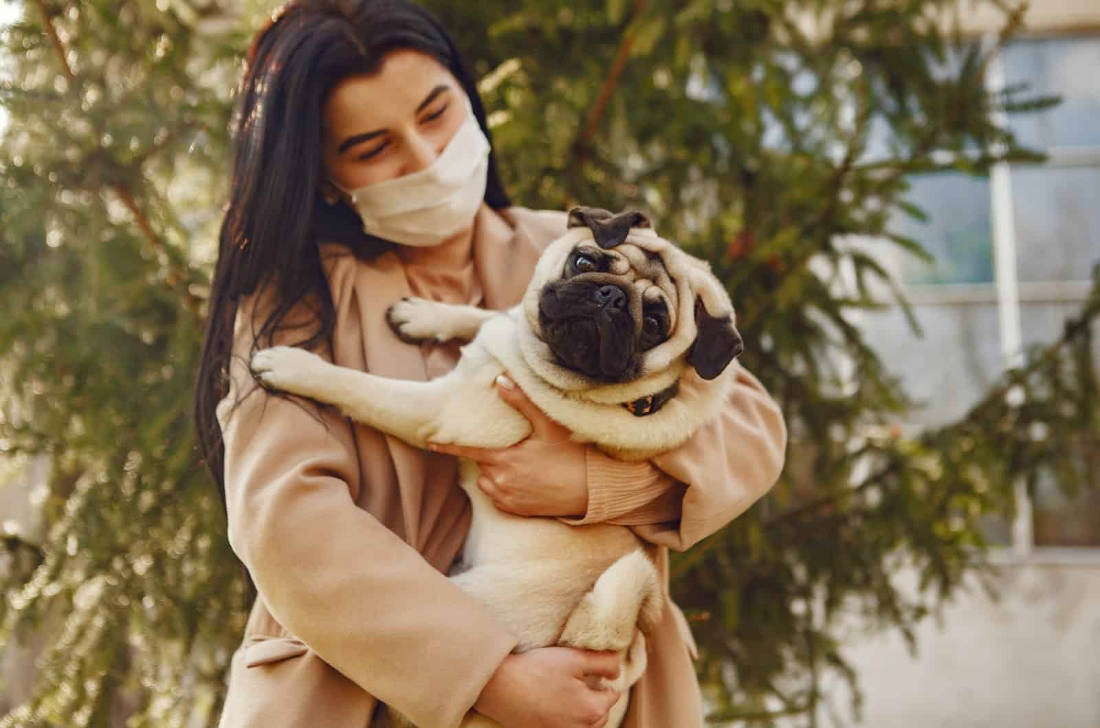 mujer sosteniendo a su mascota pug