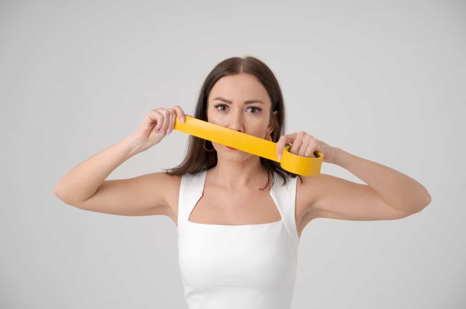 mujer sosteniendo cinta adhesiva delante de su rostro