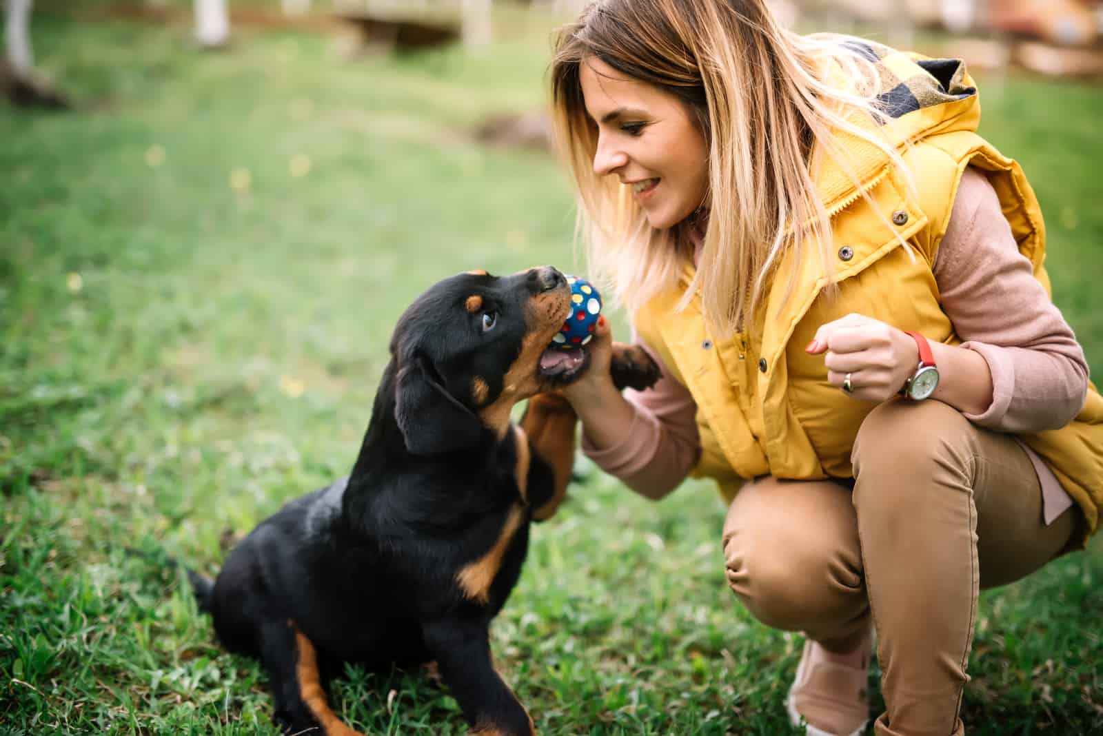mujer jugando con un cachorro de rottweiler