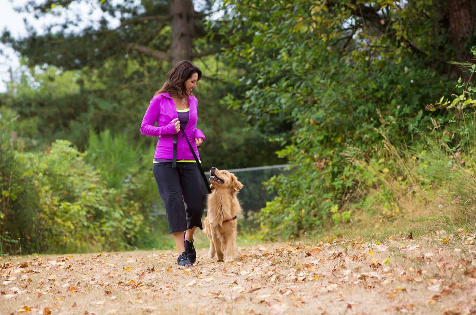 mujer caminando con su perro en la naturaleza