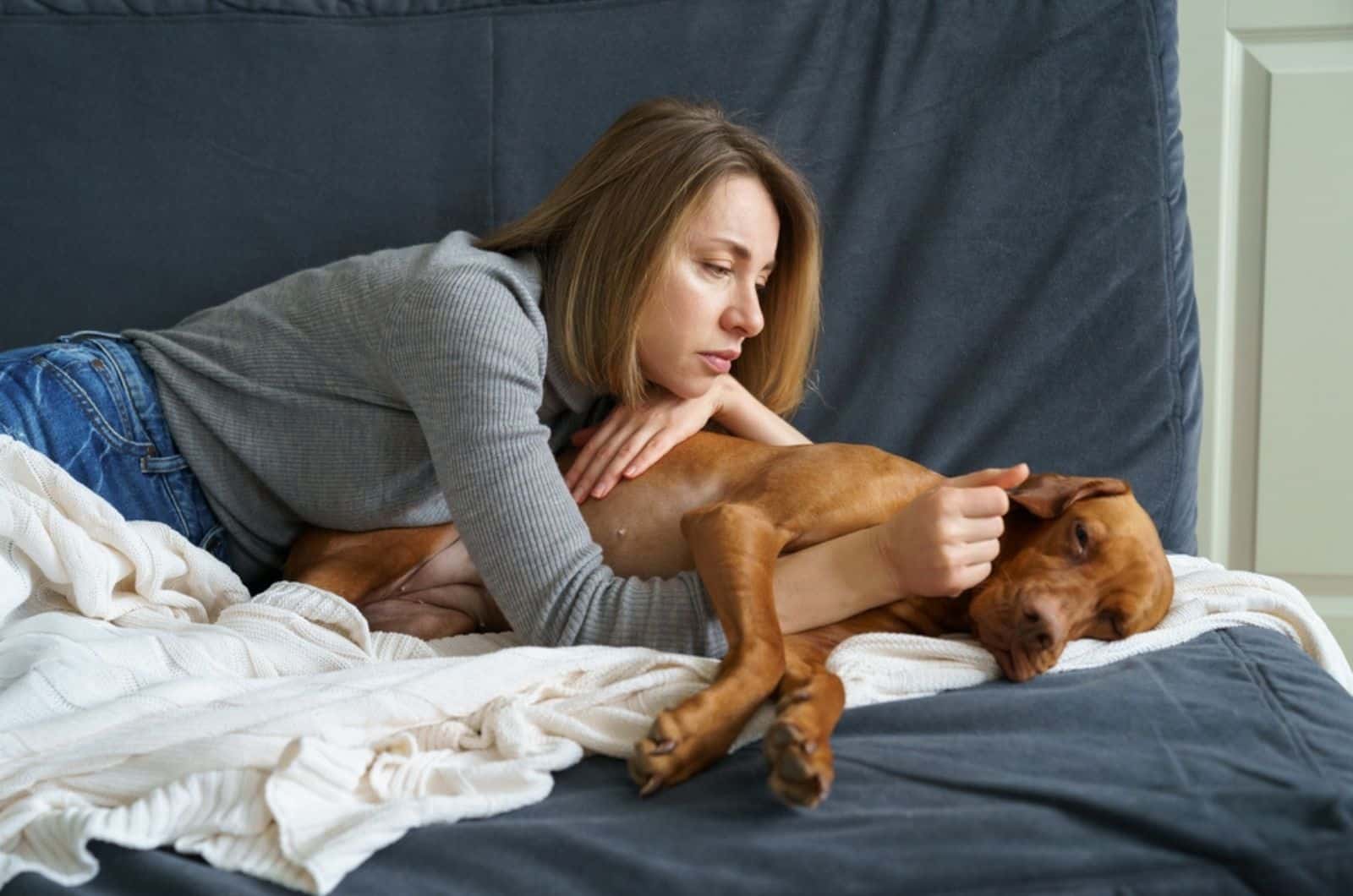 mujer preocupada cuidando a un perro débil y enfermo en casa
