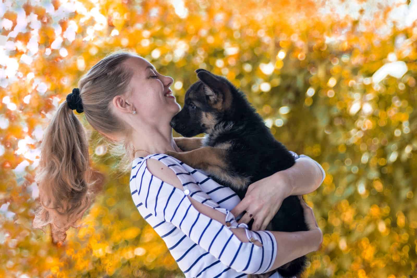 Niña feliz sosteniendo un cachorro de pastor alemán y sonriendo