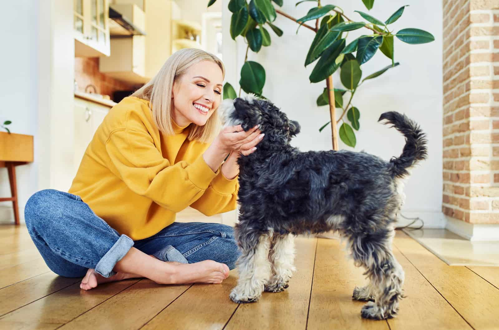 Mujer sonriente jugando con perro en casa