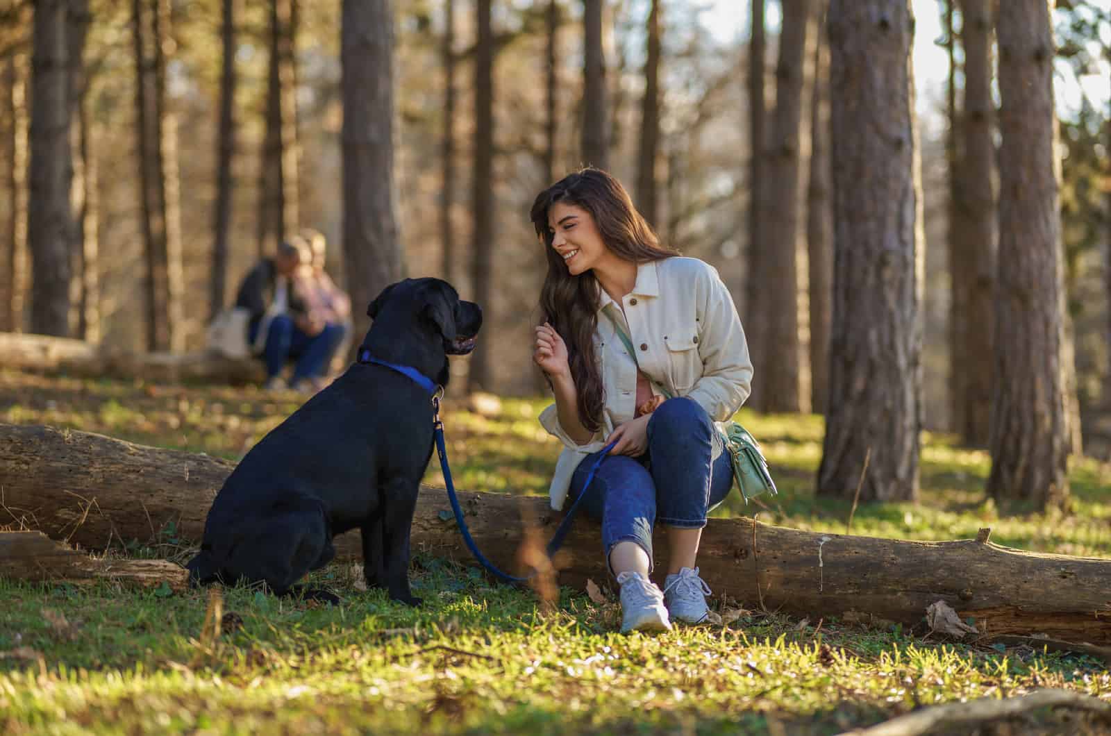 Mujer sentada con su perro en el bosque
