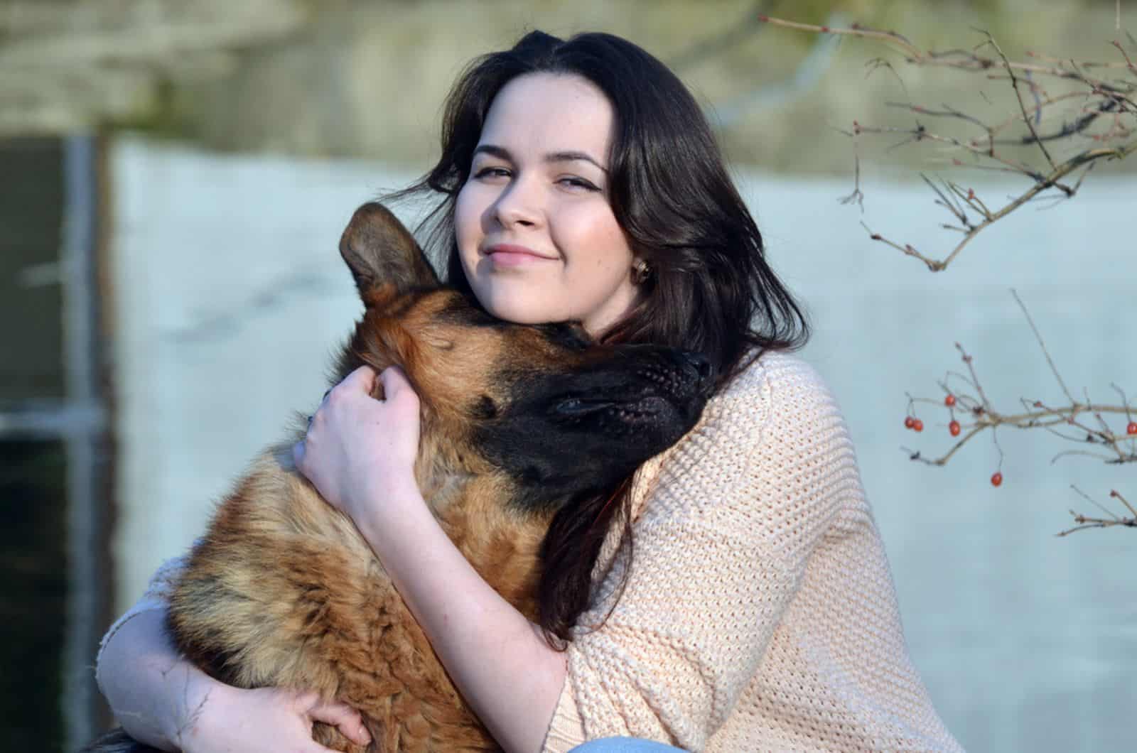 chica abrazando a su perro pastor alemán al aire libre