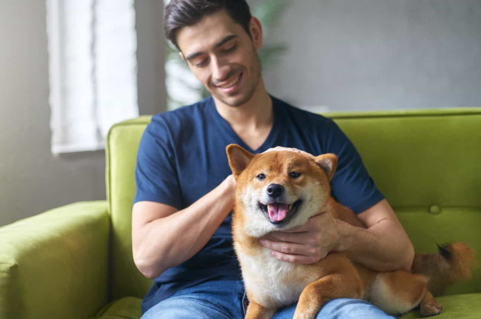 chico acariciando a su perro shiba inu en el sofá