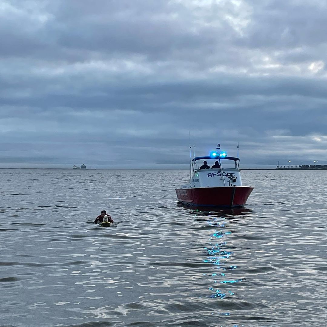salvavidas en una tabla de remo junto a un pequeño bote en el océano