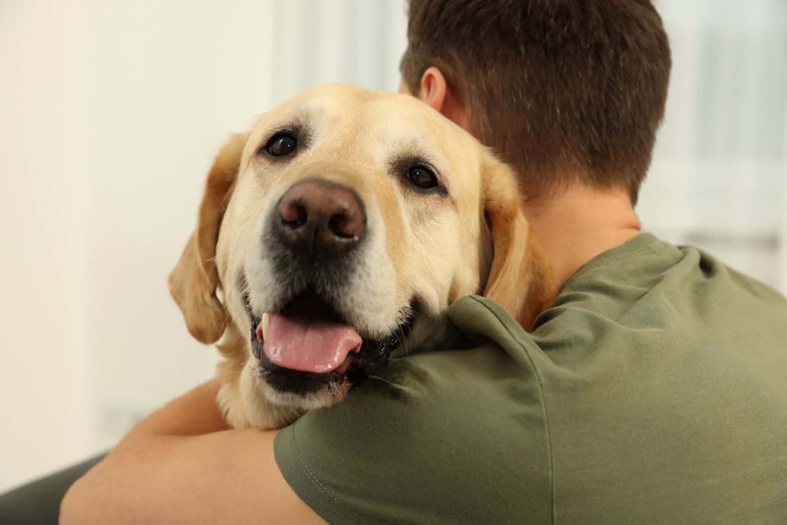 hombre abrazando un labrador retriever en casa