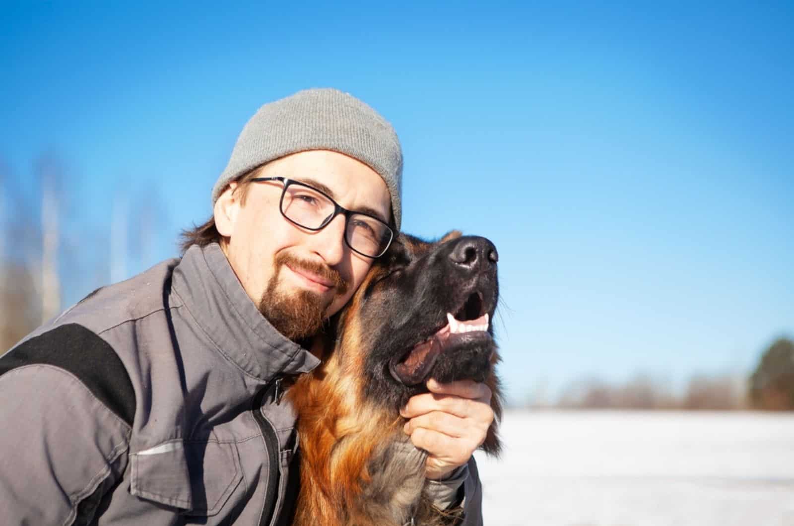 hombre con su perro pastor alemán en invierno