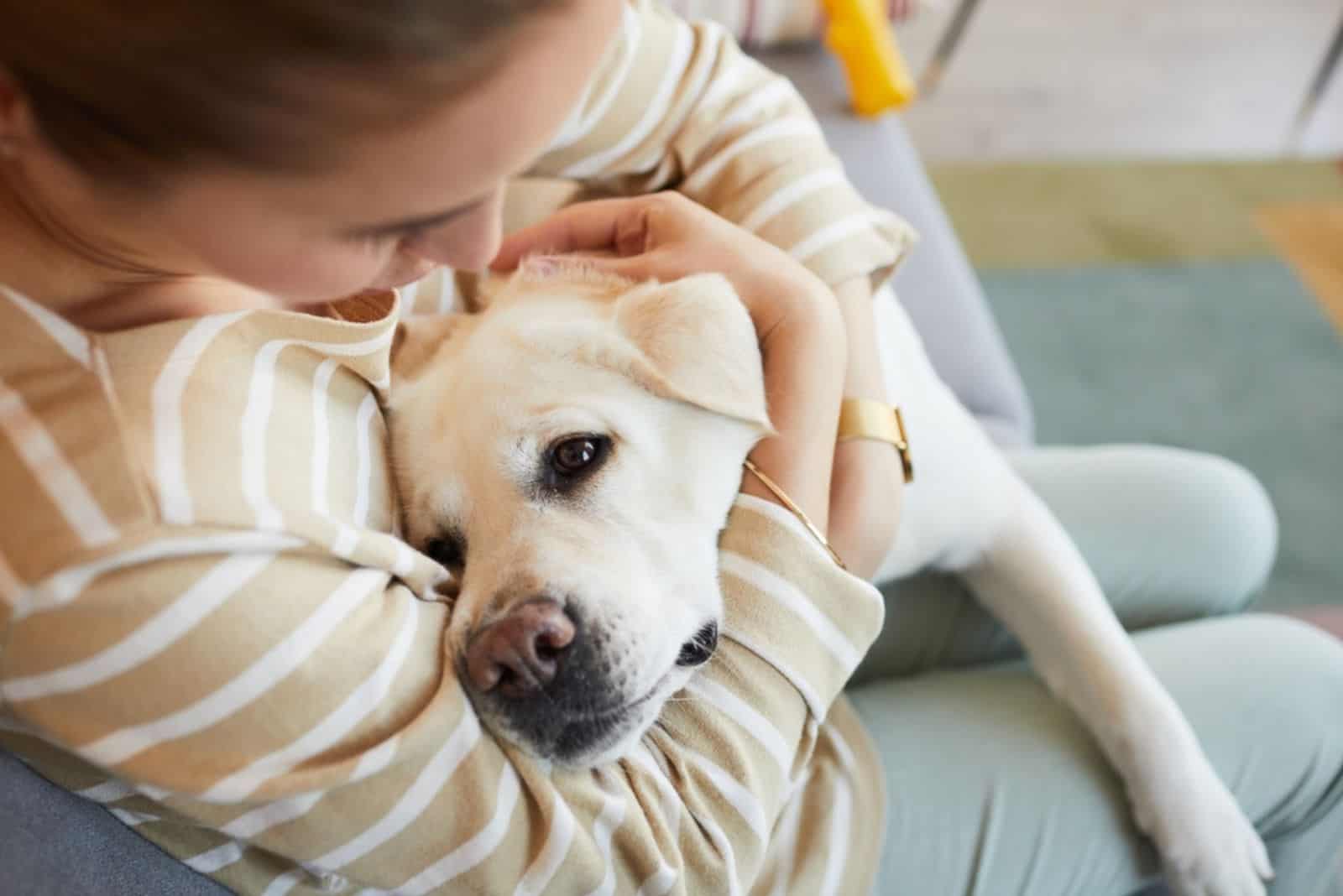 mujer abrazando a perro blanco en casa