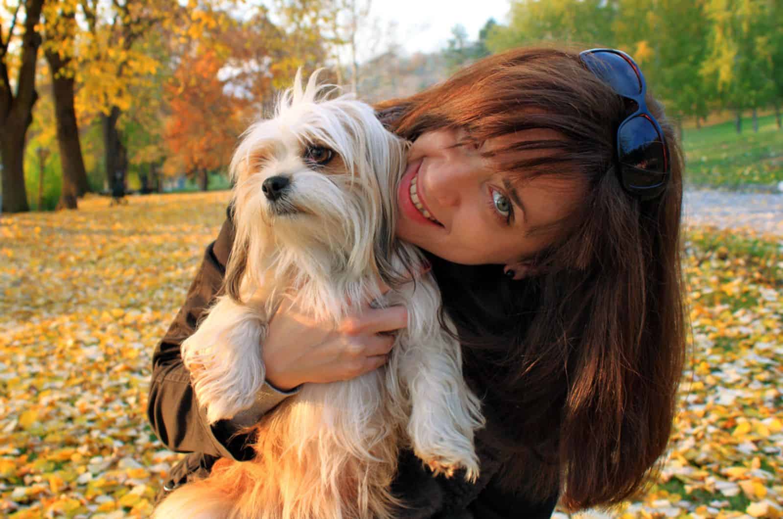 mujer sosteniendo a su lhasa apso en el parque