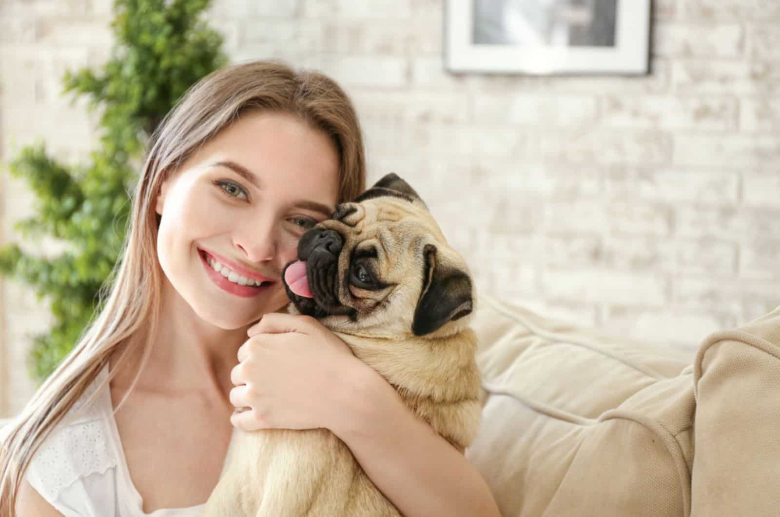 mujer abrazando a su pug en casa